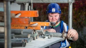 Color photo of man with Down syndrome working as a scaffolder in the building industry